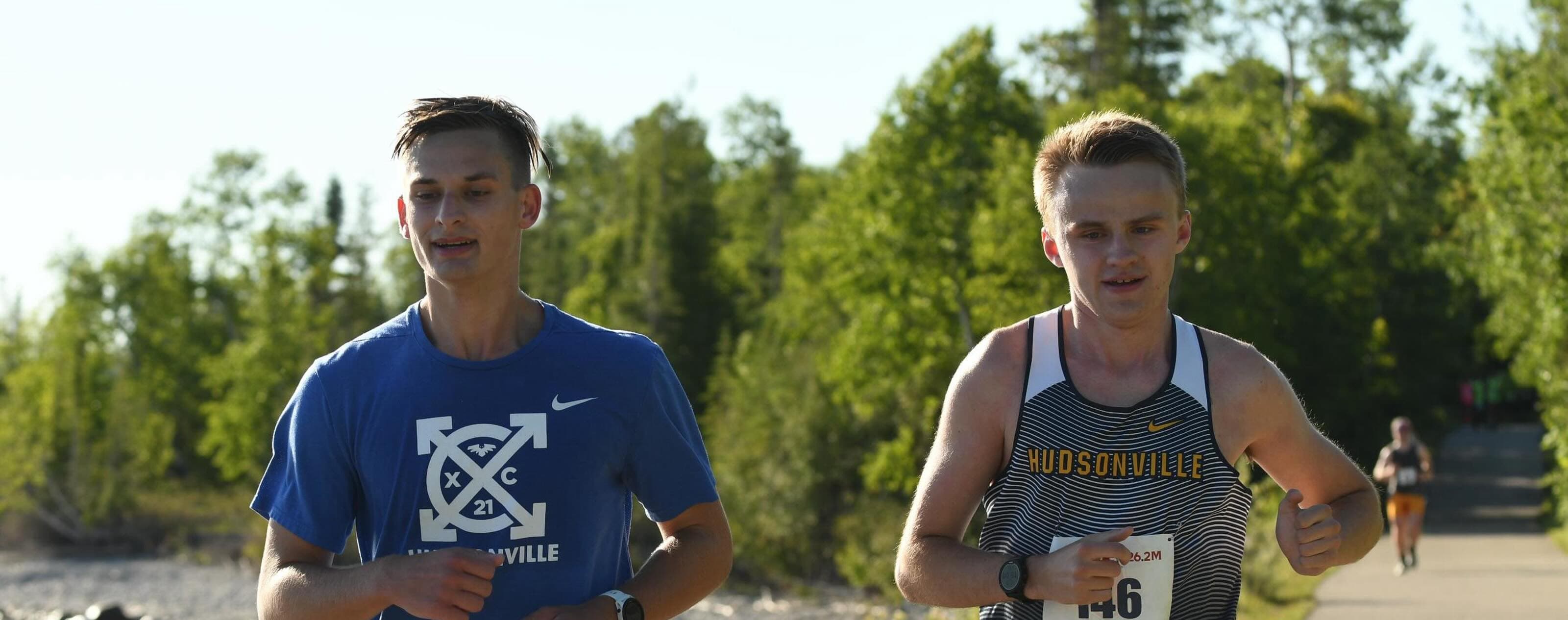 A long distance marathon runner, jogging along a wooded trail.