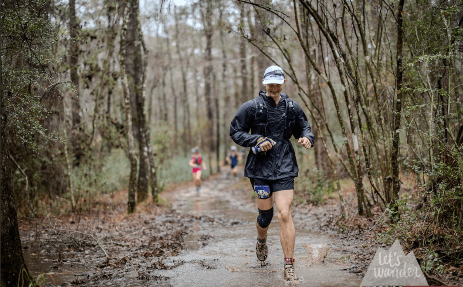 A long distance marathon runner, jogging along a wooded trail.